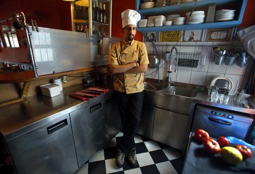 Manolis Ouranos, a 30 year-old cook, poses for a picture in the Mavros Gatos (Black Cat) tavern in Psiri neighboorhood in central Athens.