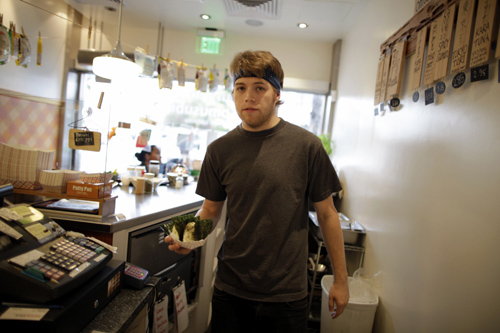 Steffen Andrews, a 24 year-old waiter, serves a customer at Sunny Blue restaurant in Santa Monica, California.