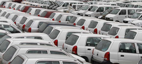 A worker adjusts the windscreen wipers of a parked car at a Maruti Suzuki stockyard on the outskirts of Ahmedabad.