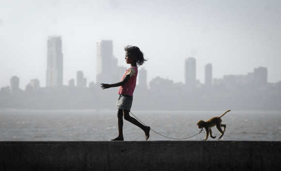 A girl walks with her pet monkey on a promenade along the Arabian Sea in Mumbai.