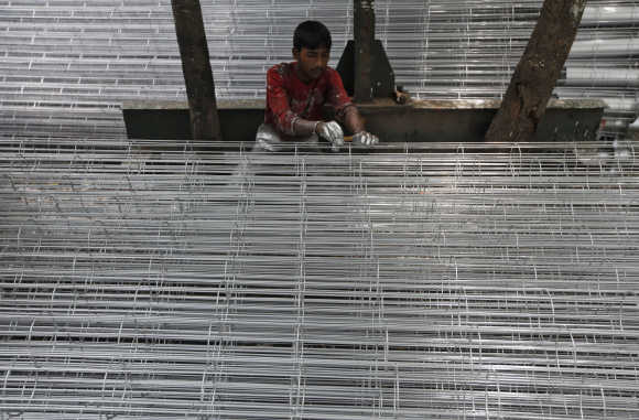 A worker paints sifts used for cement filtration at a manufacturing factory in the industrial area of Kolkata.