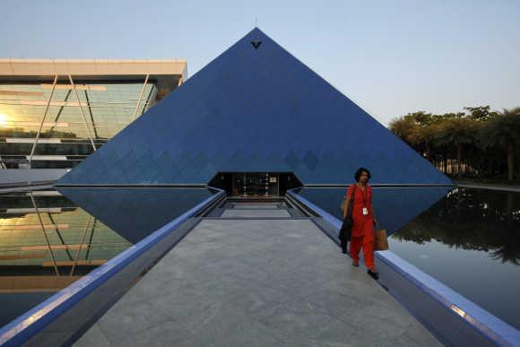 An employee walks out of an iconic pyramid-shaped building made out of glass in the Infosys campus at Electronics City in Bangalore.