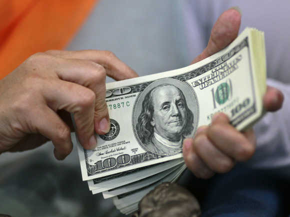 A woman counts her dollar bills at a money changer.