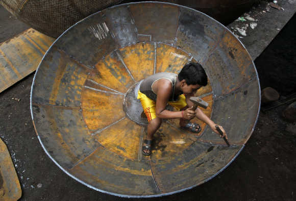 A boy checks the joints of a giant utensil at an iron utensils manufacturing unit in Kolkata.