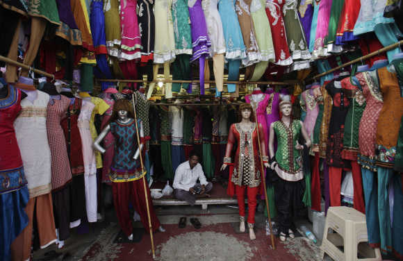 A vendor waits for customers at his shop selling clothes at a market in Mumbai.
