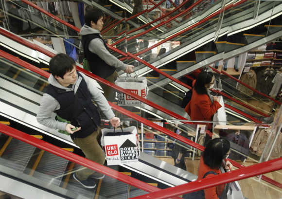 Shoppers stand on the escalator at Fast Retailing's new flagship Uniqlo store at Tokyo's Ginza district.