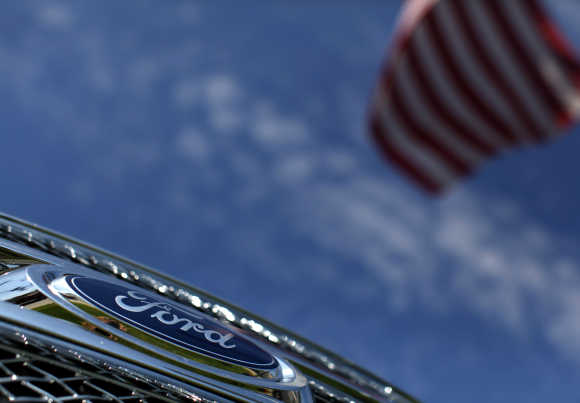 A Ford truck sits for sale under an American flag at a dealership lot in Encinitas, California.