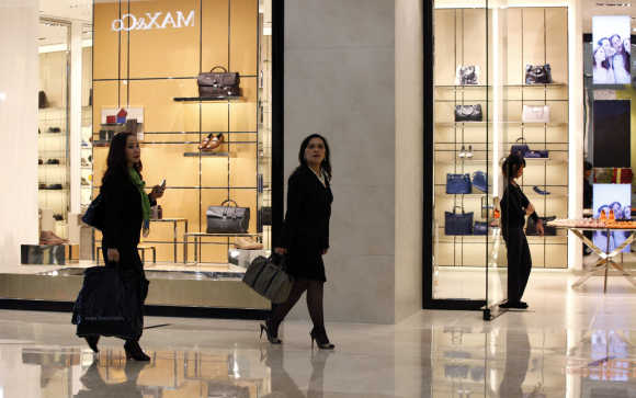 Women walk past a shop selling luxury shoes and bags at a shopping mall in Jakarta.