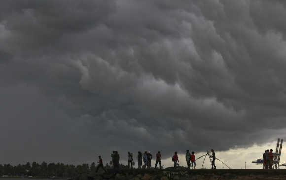 People stand on a seaside promenade against the background of pre-monsoon clouds gathered over the Arabian Sea at Kochi in Kerala. A file photo.