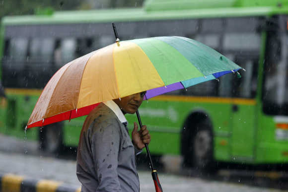 Image: A man holds his umbrella as he crosses a road during rains in New Delhi. A file photo. Photographs: Mukesh Gupta/Reuters