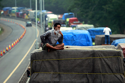 Driver Aditya Gumay smokes a cigarette on top of his truck while stuck in traffic, about 8 km (5 miles) from the port of Merak near Cilegon, Banten province.