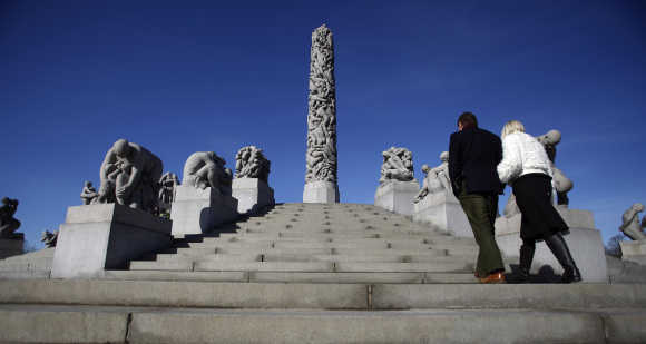 Couple walks past The Monolith sculptures in the Vigeland Sculpture Park in Oslo.