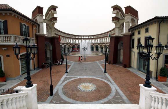 Two women walk through a building that resembles a Roman Coliseum at the Florentia Village in Wuqing, Tianjin, China.