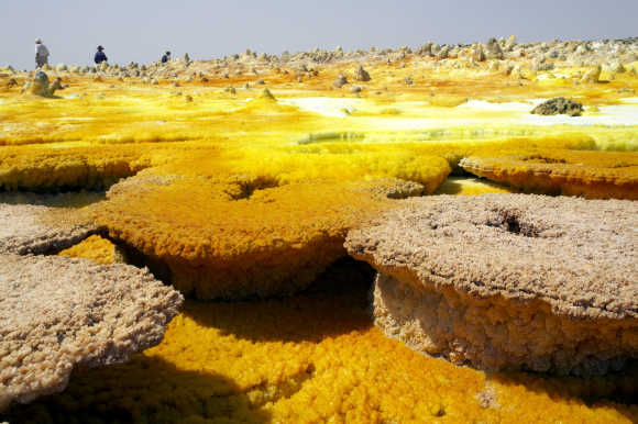 Tourists guarded by local policemen visit sulphur and mineral salt formations created by the upwelling springs of Dallol volcano, Ethiopia.