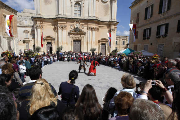Visitors watch re-enactors perform sword fights during the Medieval Mdina Festival in Mdina, Malta's former capital city.