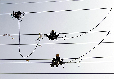 Labourers remove kites tangled up in electric power cables.