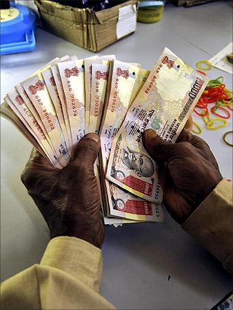 A bank employee counts currency notes at a cash counter in Agartala.