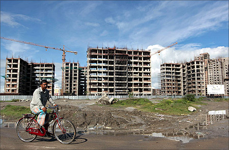A man rides a bicycle in front of the construction site of a residential complex in Kolkata.