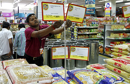 A worker of a food superstore arranges price tags of the products inside a mall in the western Indian city of Ahmedabad.