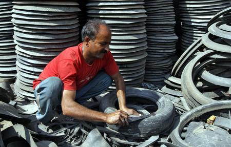 A worker dismantles a worn-out rubber tyre for recycling at a workshop in Srinagar.