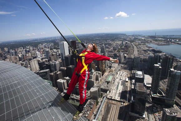 A reporter leans over the edge of the catwalk during the media preview for the EdgeWalk on the CN Tower in Toronto.