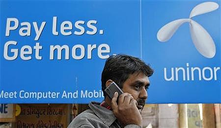 A man speaks infront of a Uninor billboard.