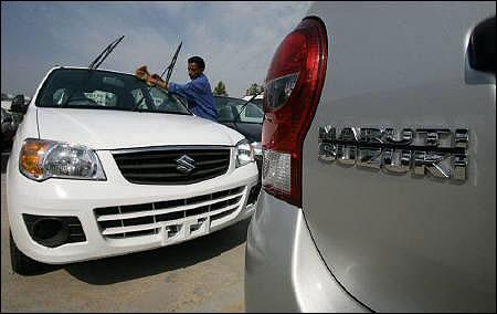 A worker cleans a parked car at the Maruti Suzuki's stockyard.