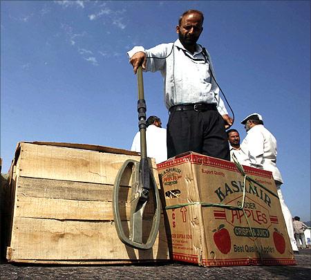 An Indian policeman checks cartons containing fruits and vegetables with a metal detector at an immigration centre.