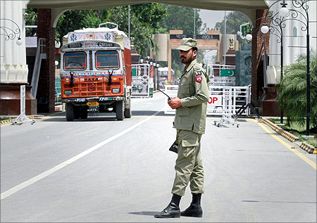 A paramilitary soldier stands guard as a truck carrying wheat crosses into Pakistan from India, at the Wagah border.