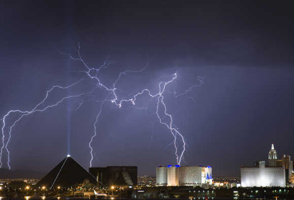 Lightning strikes behind the Luxor, left, and Excalibur, right, as a thunderstorm passes through Las Vegas.