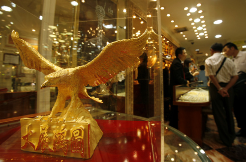 Visitors from mainland China tour a jewellery store displaying a hawk-shaped golden figurine.