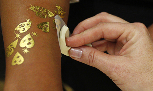 A temporary tattoo design made of gold leaf is placed on a customer's arm at a jewellery shop in Dubai.