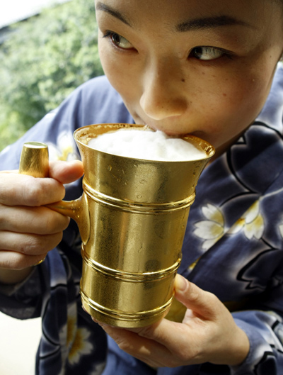 A staff member from Japanese jewellery brand Ginza Tanaka demonstrates drinking out of a solid gold beer tankard at its unveiling ceremony in Tokyo.