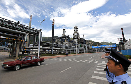 Security personnel stand guard as a car drives past the Yanshan oil refinery of Sinopec Corp. in Beijing.