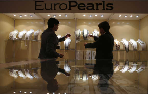 Sales representatives display pearl necklaces inside a booth at the Hong Kong Jewellery and Gem Fair.