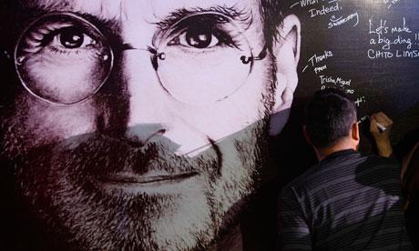 A man signs his name on a sympathy board set up for 'Steve Jobs Day'