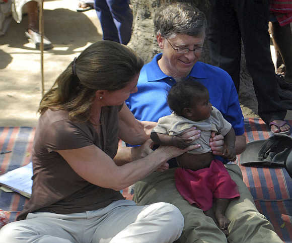 Bill Gates and wife Melinda hold a child during their visit to a Danapur slum area in Patna.