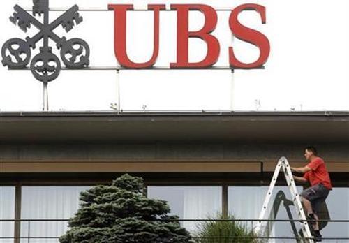 A worker climbs on a ladder under the logo of Swiss bank UBS at the company's headquarters in Zurich