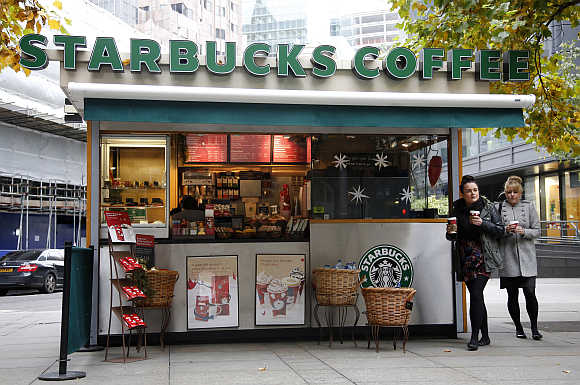 Customers leave a Starbucks coffee kiosk in the financial district of the City of London.