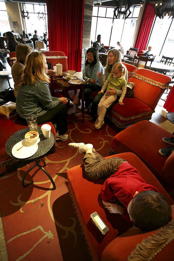 Matthew West, three, watches a video on his Mom's iPhone while she talks with friends at Starbucks' Roy Street Coffee and Tea in Seattle, Washington.