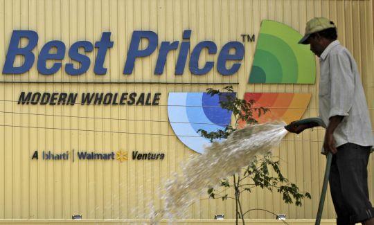 A municipal worker waters saplings near a Bharti Wal-Mart Best Price Modern wholesale store in the southern Indian city of Hyderabad