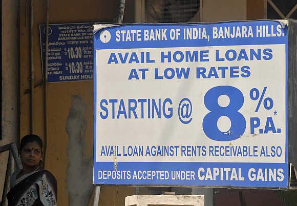 A woman stands near a bank advertisement for home loans in Hyderabad.