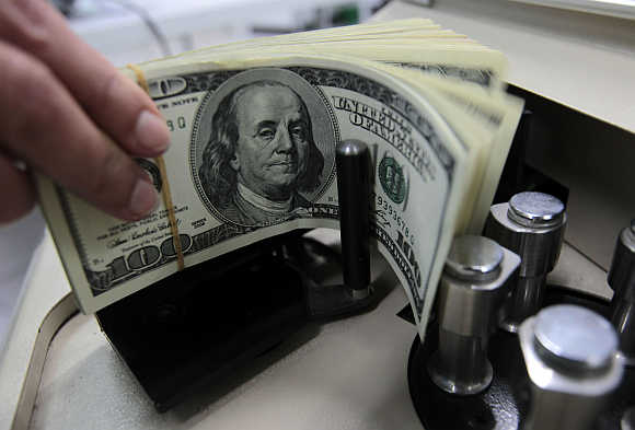 A bank employee counts dollar notes.