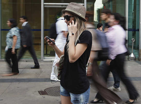 A woman uses mobile phones as she talks, writes a message and listens to music at the financial centre of Sao Paulo.