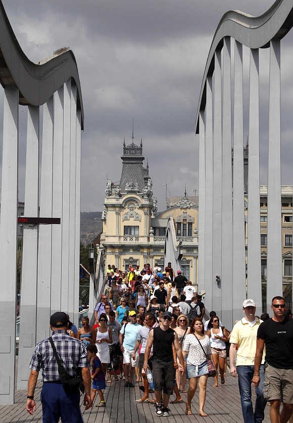 Tourists stroll along Barcelona's harbour in Barcelona.