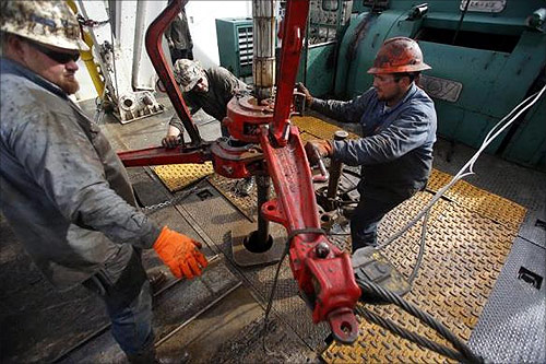 Roughnecks wrestle pipe on a True Company oil drilling rig outside Watford, North Dakota.
