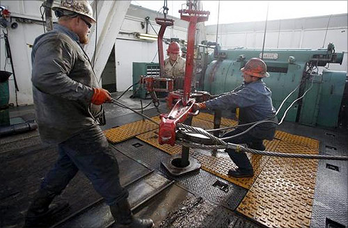 Roughnecks wrestle pipe on a True Company oil drilling rig outside Watford, North Dakota.