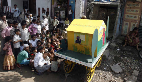 Urban poor were better-off relative to the rural poor till 1993-94, says Lahiri. Children watch a cartoon show on television on a mobile cart in Dharavi in Mumbai.