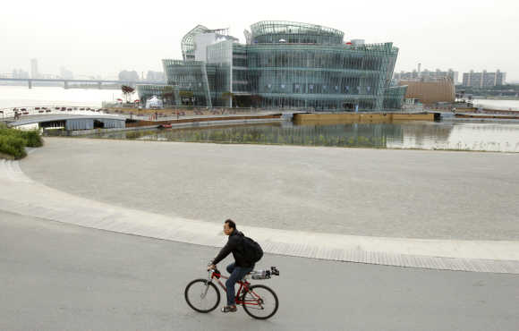 A man rides a cycle besides the Floating Island on Han River in Seoul.