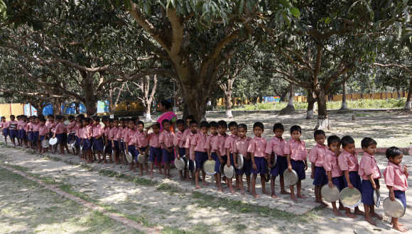 Children hold plates as they stand in line to collect their free mid-day meal in Kolkata.